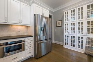 A Modern stainless steel kitchen with an under the counter Oven, a full double door stainless steel fridge and sleek counters. 